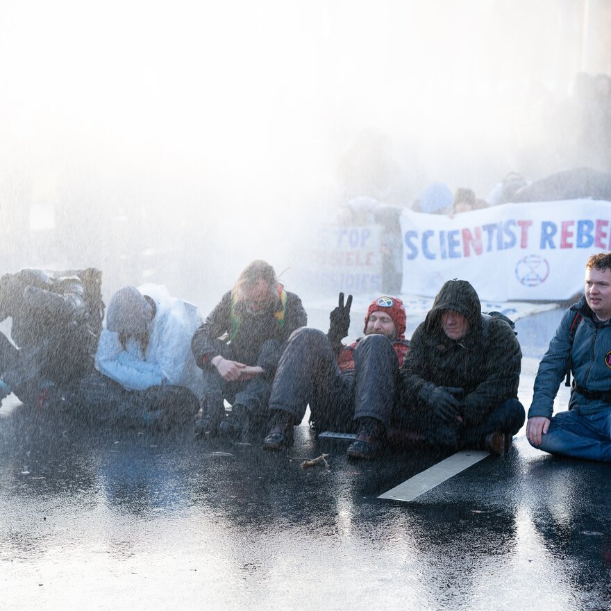 Protesters sitting down in front of water cannon 